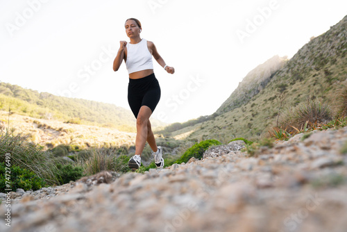 Young caucasian female athlete jogging running outdoors in sporty clothes. Training yoga sporty activity in the mountains. Slimming, burning calories concept