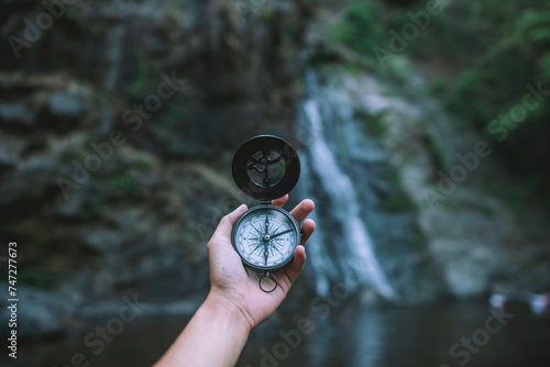 Hand holding a compass in the forest