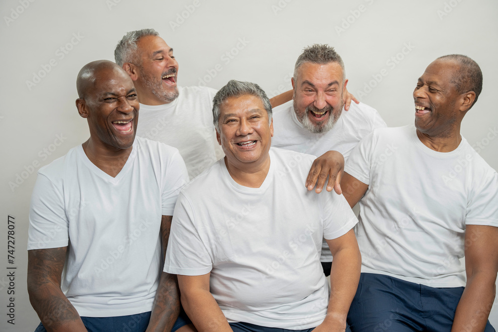 Group portrait of senior men in white t-shirts laughing against gray background Group portrait of senior men in white t-shirts laughing against gray background