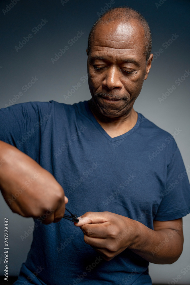 Portrait of man cutting nails against gray background