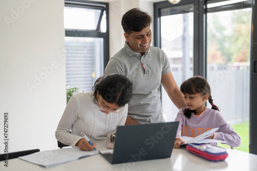 Father helping daughters doing homework