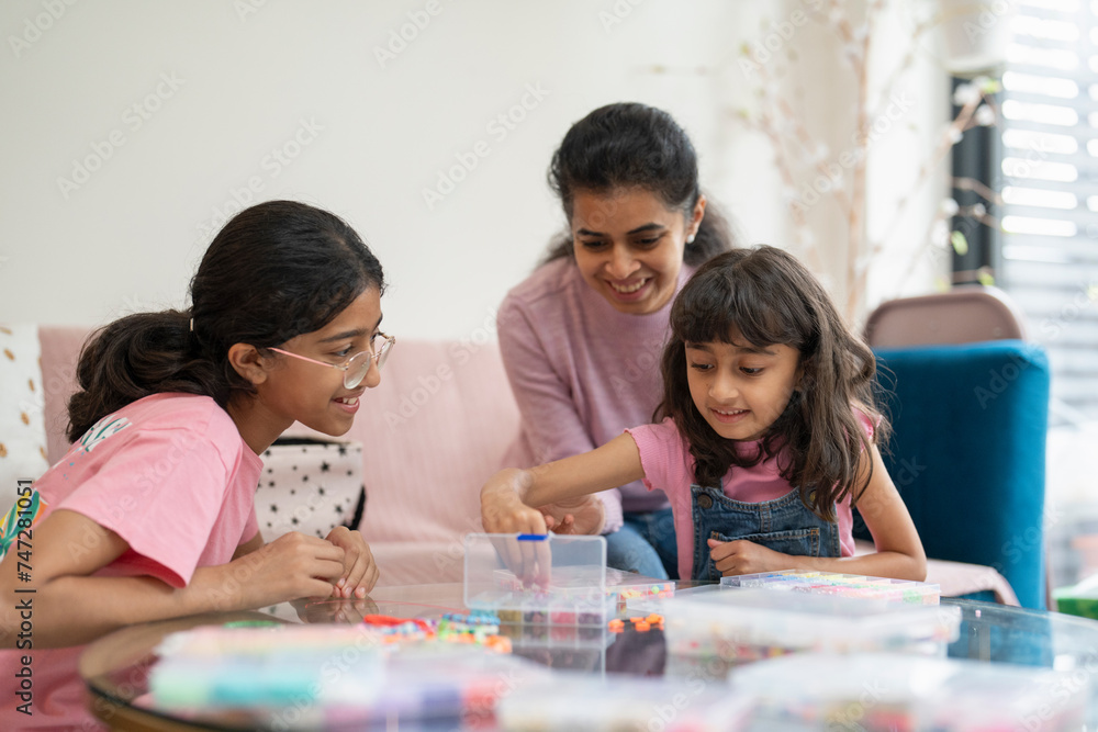Mother with daughters playing with beads in living room Mother with daughters playing with beads in living room