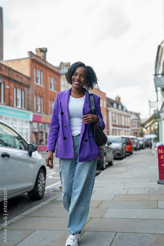 Smiling woman in purple jacket walking in city