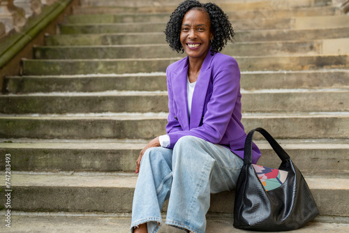 Portrait of smiling woman sitting on steps in city photo