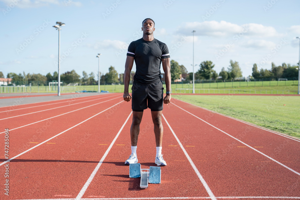 Athlete standing in front of starting line at running track Athlete standing in front of starting line at running track
