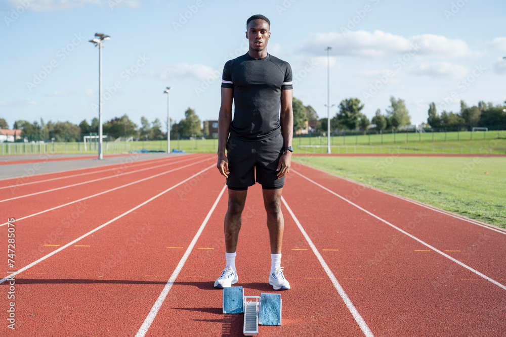 Athlete standing in front of starting line at running track Athlete standing in front of starting line at running track