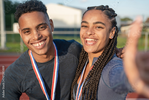 Portrait of male and female athlete celebrating with medals photo