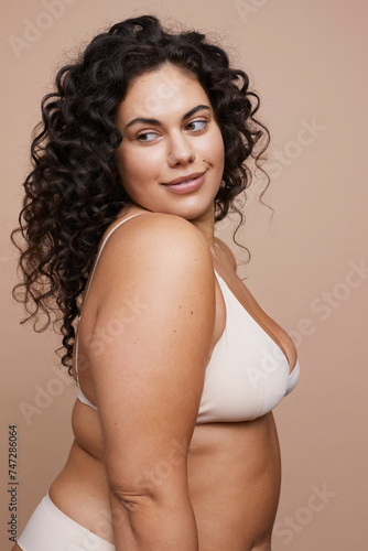 Studio shot of young woman with curly hair wearing bra
