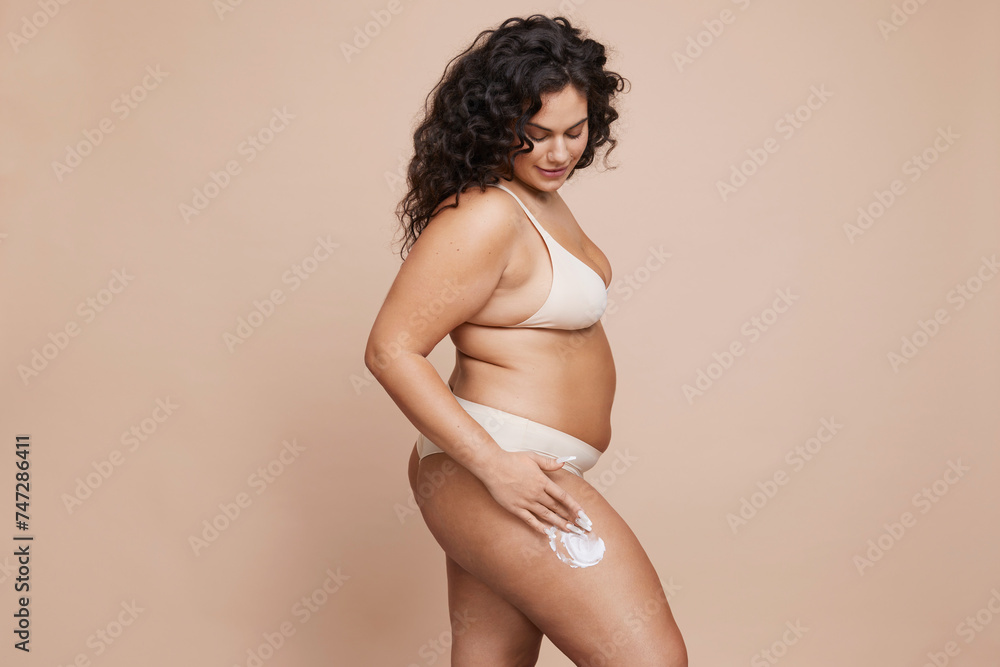 Studio shot of young woman using anti-cellulite cream Studio shot of young woman using anti-cellulite cream
