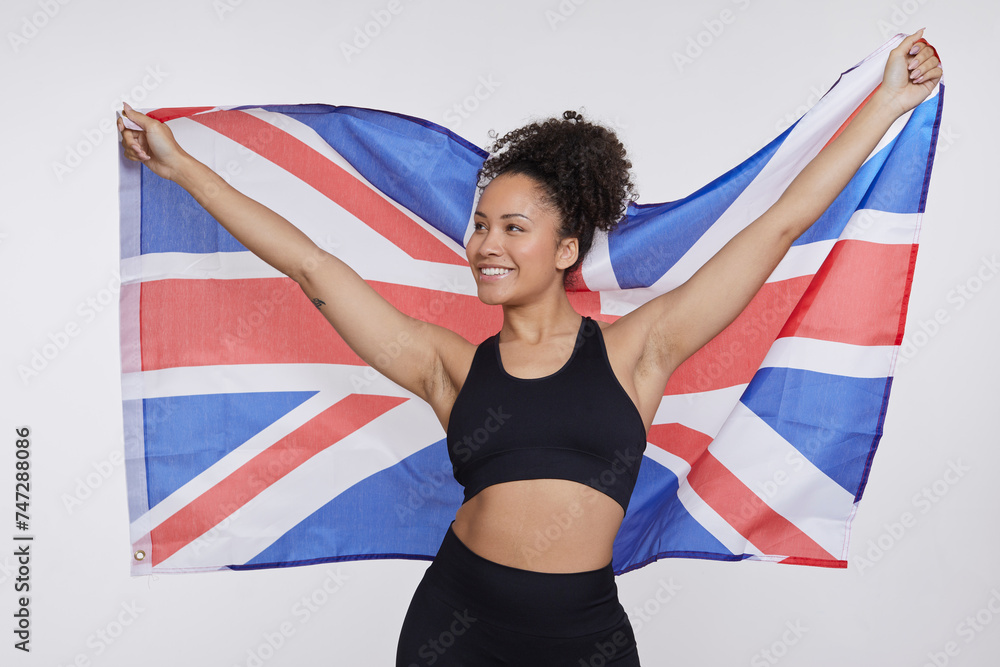 Fototapeta premium Studio portrait of smiling athletic woman holding British flag