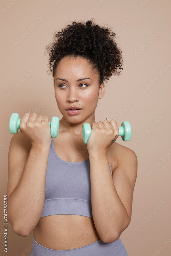 Studio portrait of woman exercising with dumbbells Studio portrait of woman exercising with dumbbells