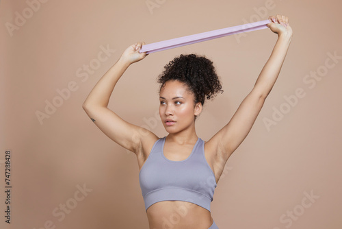 Studio portrait of athletic woman exercising with resistance band © Cultura Creative