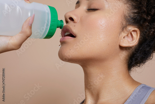 Close-up of athletic woman with sweat of face drinking water