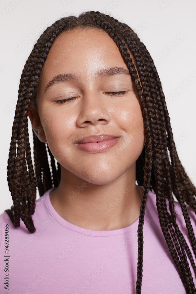 Studio portrait of smiling girl with braided hair and eyes closed Studio portrait of smiling girl with braided hair and eyes closed