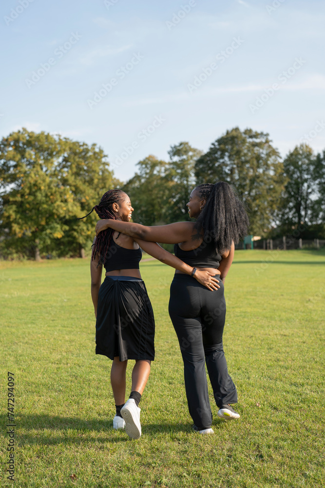 Young female friends walking in park after exercising Young female friends walking in park after exercising