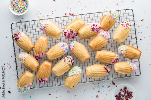 Beautifully decorated Madeleines on a cooling rack with sprinkles all around. photo