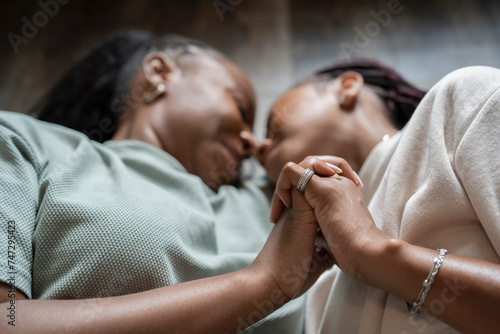Close-up of lesbian couple holding hands while lying on floor