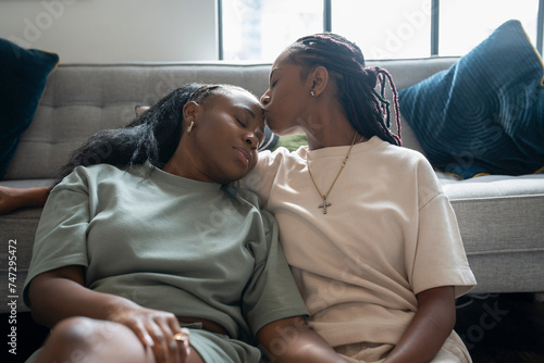 Lesbian couple kissing while resting in living room