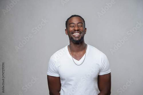 Portrait of smiling man with closed eyes, wearing white t-shirt and necklace