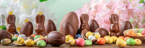 Easter background greeting card with holiday traditional confectionery, Easter egg hunt fun concept. Chocolate bunny, chocolate and candy Easter eggs on wooden background