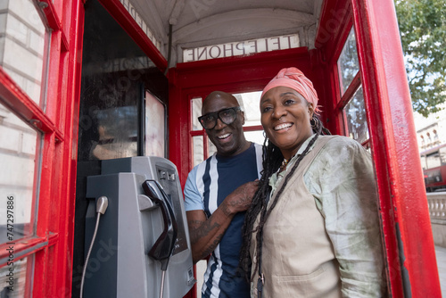 UK, London, Happy mature couple posing in traditional red telephone booth