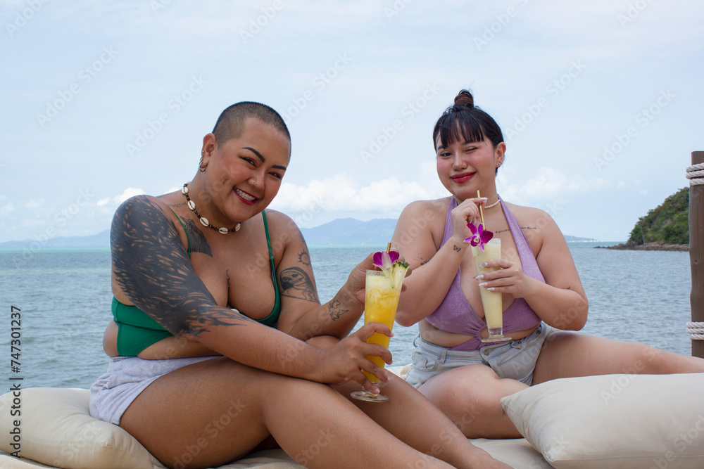 Cheerful women drinking cocktails and relaxing near bay Cheerful women drinking cocktails and relaxing near bay