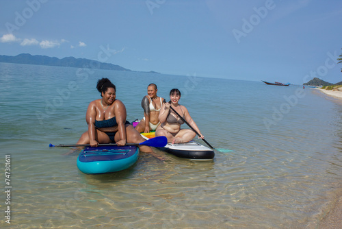 Group of cheerful women paddleboarding in sea