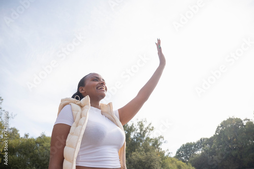 Smiling young woman waving outdoors