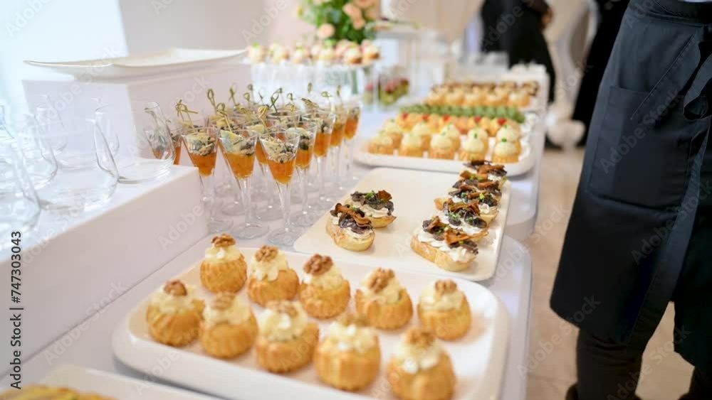 The waiter places the finished sandwiches on the table with treats. Catering. The waiter places the finished sandwiches on the table with treats. Catering.
