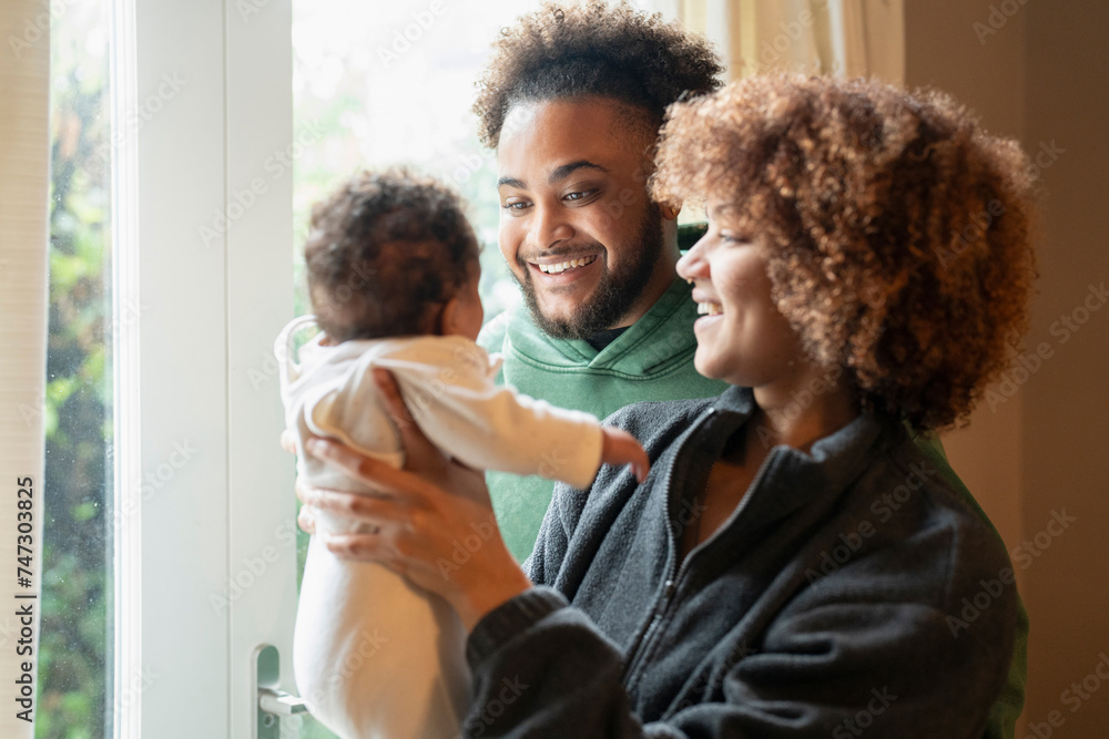 Smiling parents looking at baby daughter at home Smiling parents looking at baby daughter at home