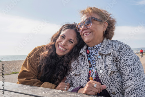 Mother and daughter resting by picnic table on beach photo