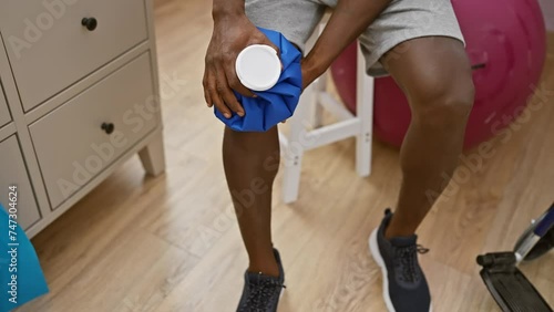 African american man in physiotherapy clinic using ice pack on knee photo