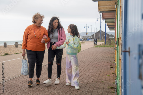 Grandmother, mother and granddaughter walking by beach huts