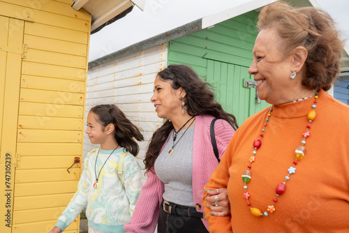 Grandmother, mother and granddaughter walking by beach hut photo