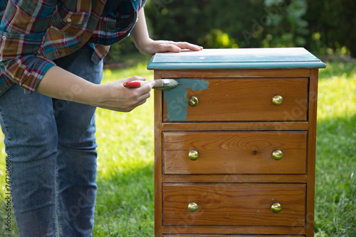 Painting a wooden furniture outdoors, an eco-friendly re-use business.