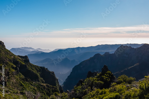 Scenic view of misty hills and cloud covered coastline of majestic Atlantic Ocean on Madeira island, Portugal, Europe. Idyllic hiking trail to mountain peak Pico Ruivo. Coastal landscape on sunny day © Chris