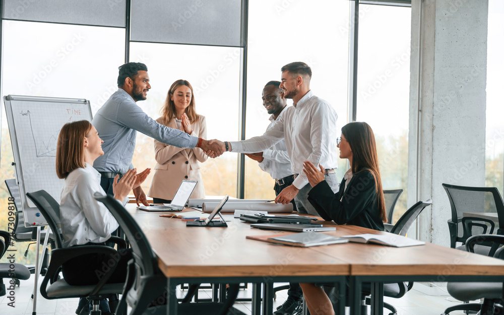 Successful agreement, making handshake. Group of office workers are together indoors