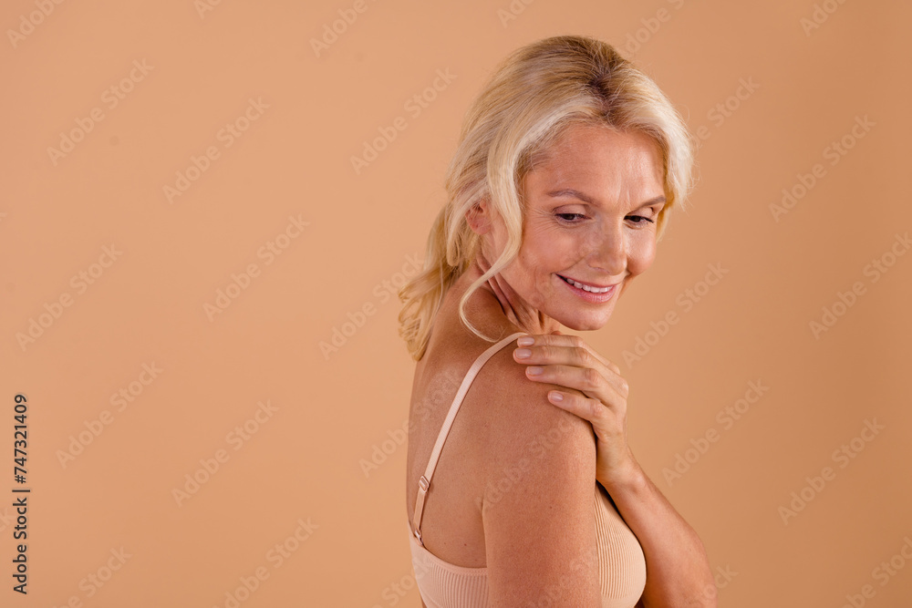 Profile side photo of charming pensioner hand touch shoulders soft pure fresh silky skin empty space isolated on beige color background Profile side photo of charming pensioner hand touch shoulders soft pure fresh silky skin empty space isolated on beige color background