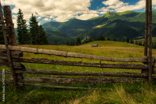 Wooden vintage fence, barn in a meadow in the mountains.