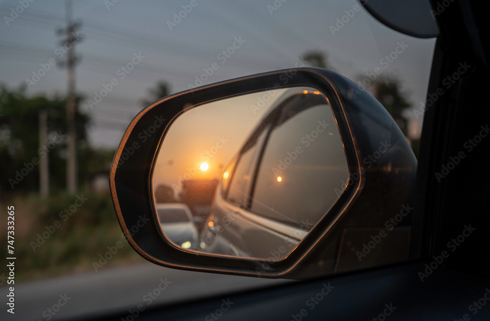 reflection of traffic flow in side rear view mirror at  twilight time sun set of sky.