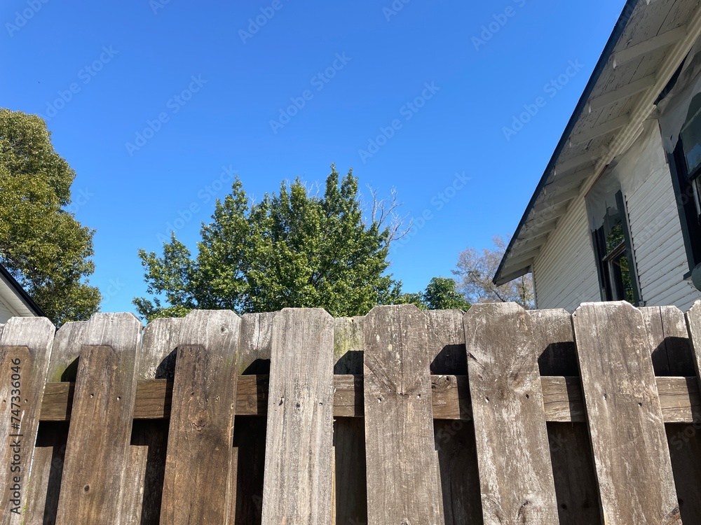 Brown wooden fence shadow box style blue sky summer background looking up