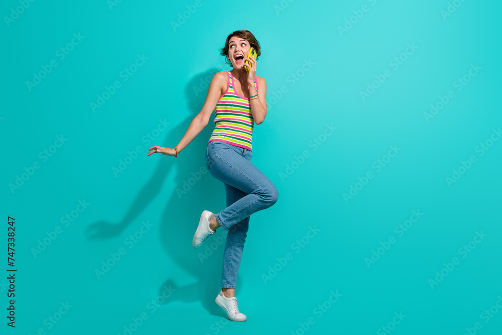 Full length portrait of astonished positive person speak telephone empty space isolated on turquoise color background