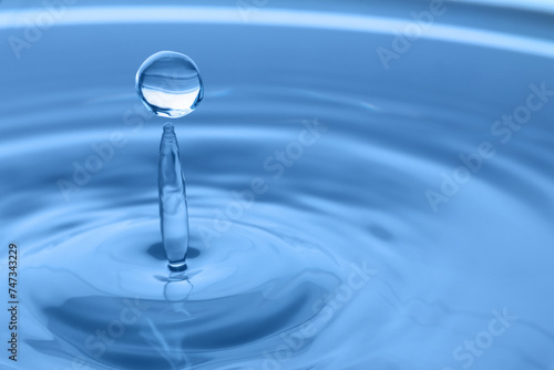 Splash of clear water with drop on light grey background, closeup. Space for text