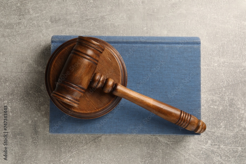 Wooden gavel, sound block and book on grey textured table, top view