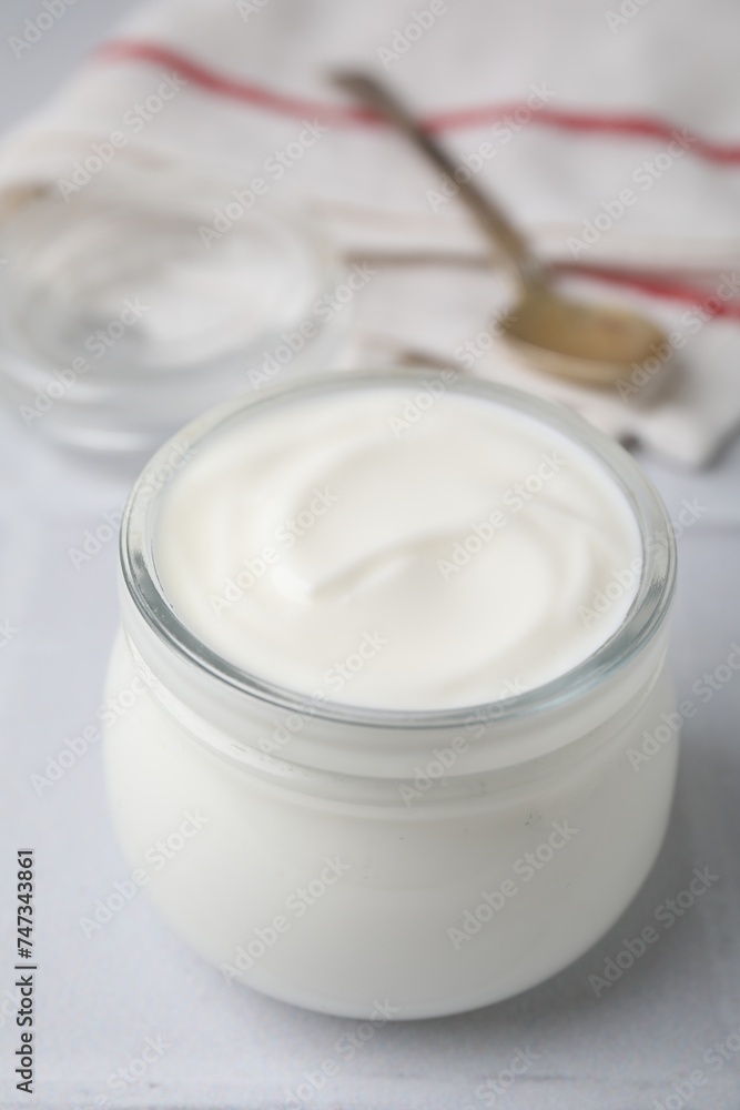 Delicious natural yogurt in glass jar on white table, closeup Delicious natural yogurt in glass jar on white table, closeup