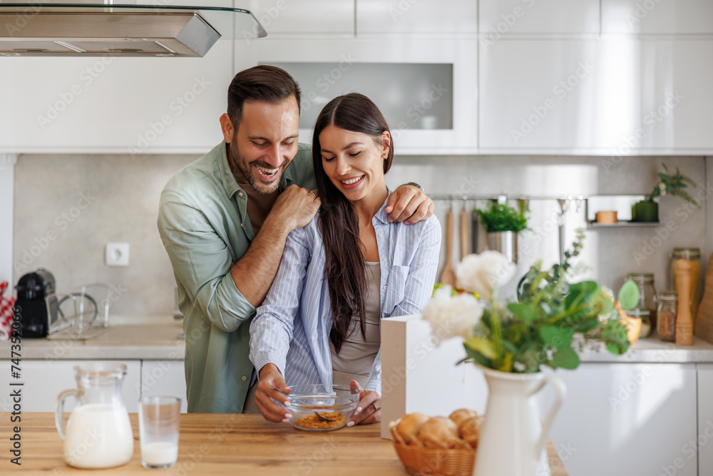 Happy young couple enjoying breakfast together in kitchen