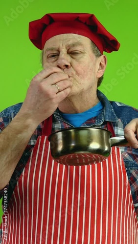 Senior gourmet chef smelling food aroma from stewpan enjoying of smell of food. photo