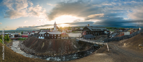 Super panorama of evening sun casts a warm glow over Roros, Norway, highlighting the town's heritage architecture and the rugged beauty of its mining landscape from above photo