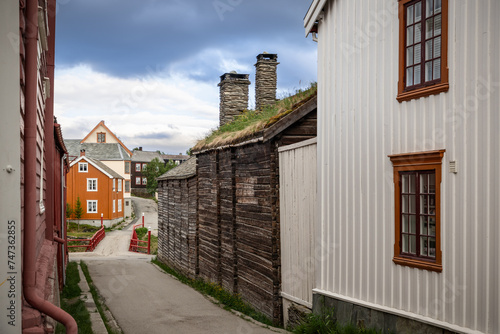 Nestled within the historic village of Roros, this street view captures the unique charm of timber walls and sod roofs, with a pop of color from traditional Norwegian houses photo