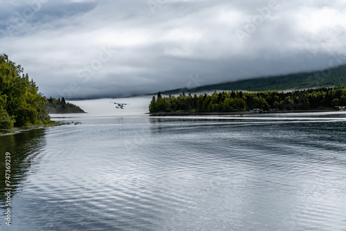 Port Alsworth, Alaska: Floatplane taking off on Hardenburg Bay on Lake Clark in Lake Clark National Park and Preserve. Inverted cloud layer, fog, Tanalian Mountain, seaplane, reflection. photo